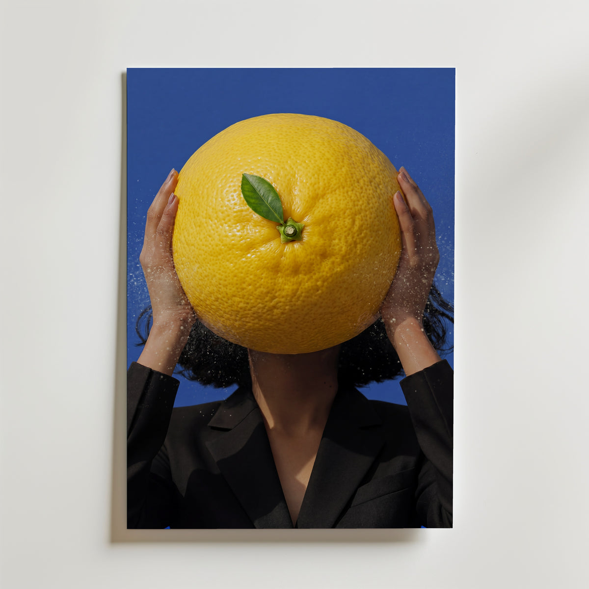 Citrus Surge Poster – kvinna håller jättelik citrusfrukt framför ansiktet mot koboltblå bakgrund